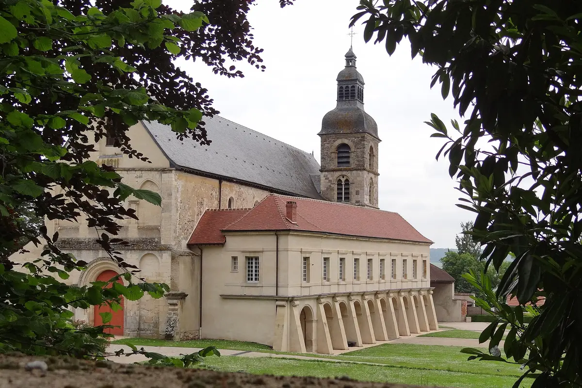 L'abbazia e il chiostro di Hautvillers visti tra gli alberi, con un campanile in pietra e un tetto di tegole rosse